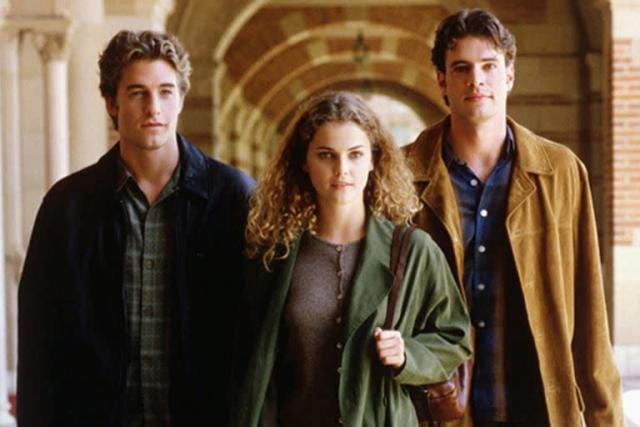 A atriz Keri Russell (Felicity) caminhando pelos corredores da faculdade ao lado dos atores Scott Speedman (Ben) e Scott Foley (Noel), formando o famoso triângulo amoroso da série Felicity.