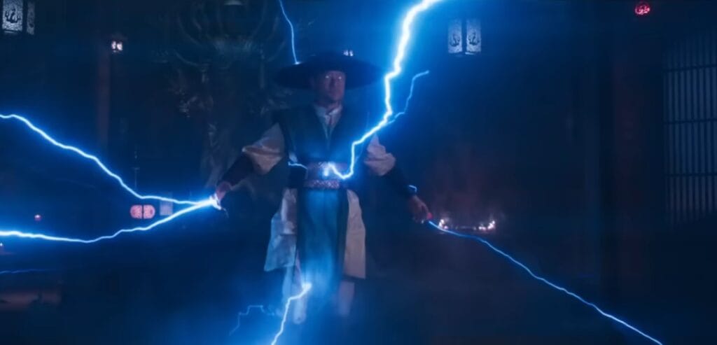 Raiden (Tadanobu Asano) levitando com olhos brilhando em branco e cercado por raios azuis poderosos em uma cena de Mortal Kombat 2 (2026). Ele veste seu traje clássico de protetor da Terra com o chapéu de palha em um cenário de templo sombrio e místico.