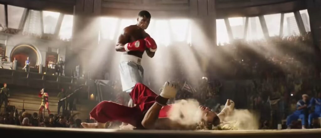 50 Cent como Balrog, em calções brancos e luvas vermelhas, de pé sobre Ken caído inconsciente em uma arena de torneio de Street Fighter O Filme 2026. Cena de knockout com iluminação dramática.