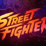 Logotipo oficial de Street Fighter O Filme 2026, com letras estilizadas em gradiente amarelo, laranja e vermelho, sobre um fundo de concreto escuro com iluminação de neon azul e roxo e faíscas.