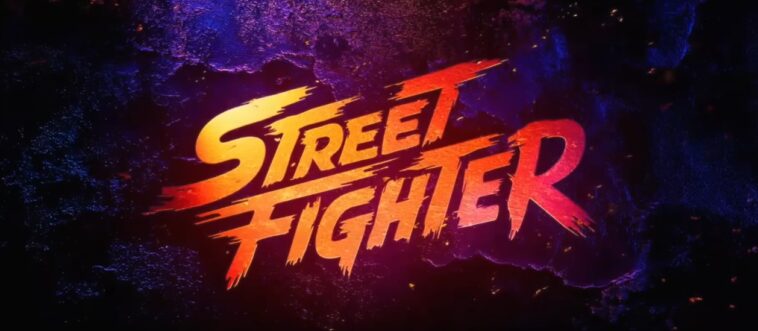 Logotipo oficial de Street Fighter O Filme 2026, com letras estilizadas em gradiente amarelo, laranja e vermelho, sobre um fundo de concreto escuro com iluminação de neon azul e roxo e faíscas.